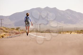 Rear View Of Woman On Vacation Hitchhiking Along Road