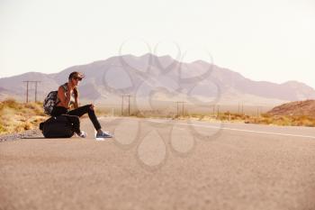 Woman On Vacation Hitchhiking Along Road Using Mobile Phone