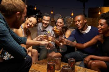 Group Of Friends Enjoying Night Out At Rooftop Bar