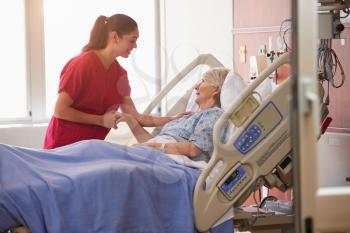 Nurse Talking To Senior Female Patient In Hospital Bed
