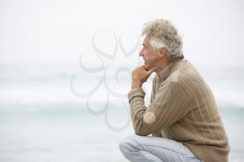 Senior Man On Holiday Kneeling On Winter Beach