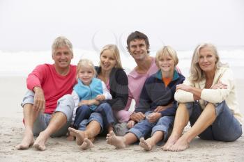 Three Generation Family Sitting On Winter Beach Together