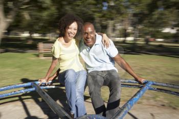 Young Couple Riding On Roundabout In Park