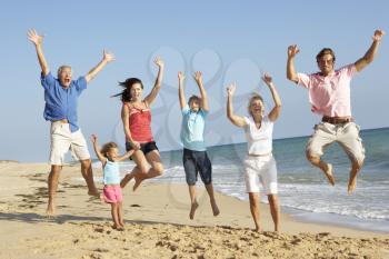 Portrait Of Three Generation Family On Beach Holiday Jumping In Air