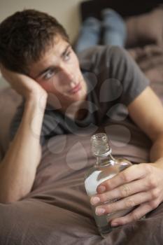 Teenage Boy Lying  In Bedroom Drinking