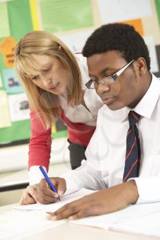 Teenage Student Working In Classroom With Teacher