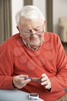 Senior Man Checking Blood Sugar Level At Home