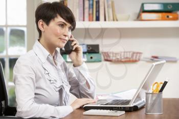 Woman Working From Home Using Laptop On Phone