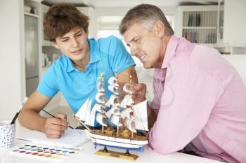 Father and teenage son model making and painting