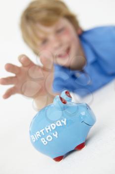 Young boy reaching for piggy bank