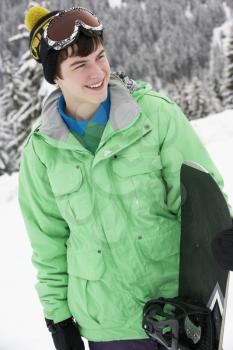 Teenage Boy With Snowboard On Ski Holiday In Mountains