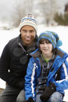 Portrait Of Father And Son Wearing Winter Clothes In Snowy Landscape