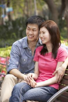 Young Chinese Couple Relaxing On Park Bench Together