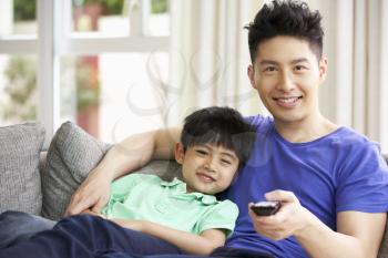 Chinese Father And Son Sitting And Watching TV On Sofa Together