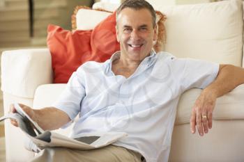 Senior Man Relaxing On Sofa At Home Reading Newspaper