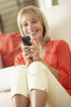 Senior Woman Relaxing On Sofa Sending Text Message