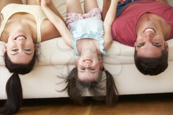 Family Lying Upside Down On Sofa With Daughter