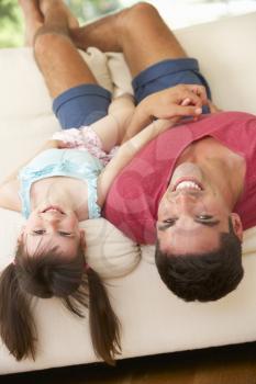 Father Lying Upside Down On Sofa With Daughter