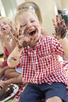 Group Of Children Eating Cake At Outdoor Tea Party