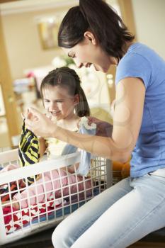 Mother And Daughter Sorting Laundry Sitting On Kitchen Counter