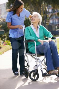 Carer Pushing Senior Woman In Wheelchair