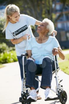 Teenage Volunteer Pushing Senior Woman In Wheelchair