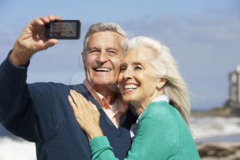 Senior Couple With Camera On Beach