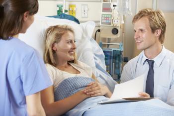 Doctor With Nurse Talking To Teenage Female Patient In Bed