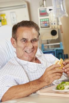 Male Patient Enjoying Meal In Hospital Bed