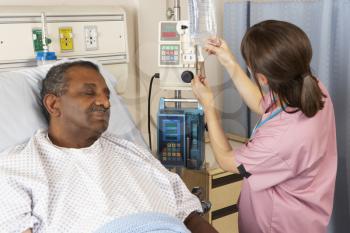 Nurse Checking Senior Male Patient's IV Drip On Ward