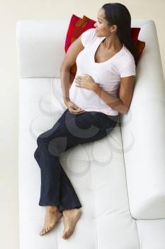 Overhead View Of Pregnant Woman Relaxing On Sofa