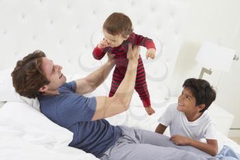 Father Playing In Bed With Children