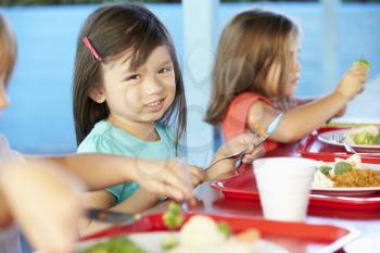 Elementary Pupils Enjoying Healthy Lunch In Cafeteria