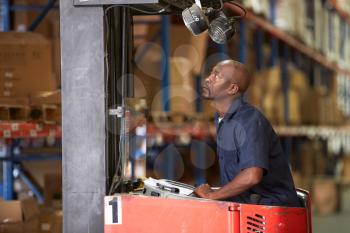 Man Driving Fork Lift Truck In Warehouse