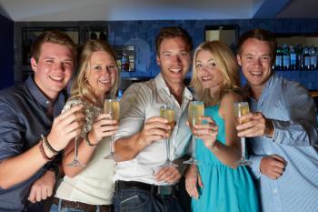 Group Of Friends Enjoying Glass Of Champagne In Bar