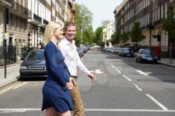 Couple With Pregnant Wife Crossing City Road