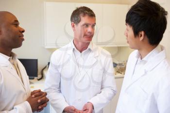 Three Doctors Having Discussion In American Hospital