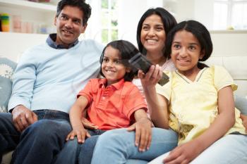 Indian Family Sitting On Sofa Watching TV Together