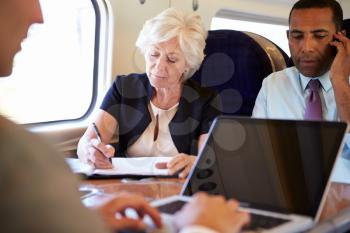 Businesspeople On Train Using Digital Devices