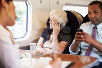 Businesswoman Using Mobile Phone On Busy Commuter Train