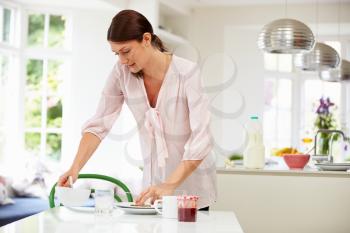 Hispanic Woman Clearing Up After Breakfast