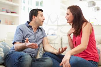 Hispanic Couple Sitting On Sofa Arguing