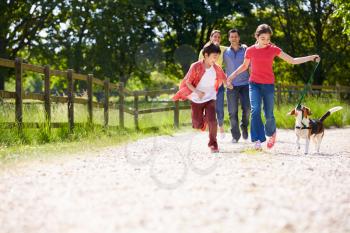 Hispanic Family Taking Dog For Walk In Countryside