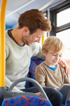 Son Using Digital Tablet On Bus Journey With Father