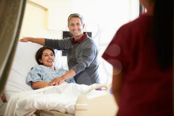 Husband Visiting Wife In Hospital And Talking To Nurse