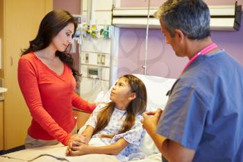 Mother And Daughter Talking To Consultant In Hospital Room