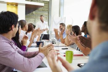 Businessman Addressing Meeting Around Boardroom Table