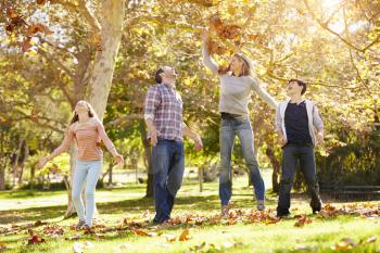 Family Throwing Autumn Leaves In The Air