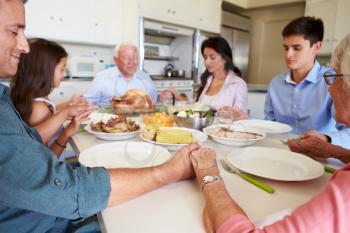 Multi-Generation Family Saying Prayer Before Eating Meal