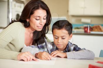 Hispanic Mother Helping Son With Homework At Table